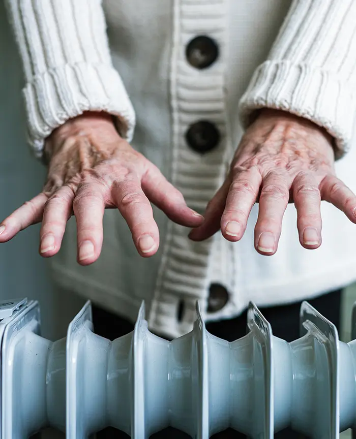 woman warming her hands on a heater